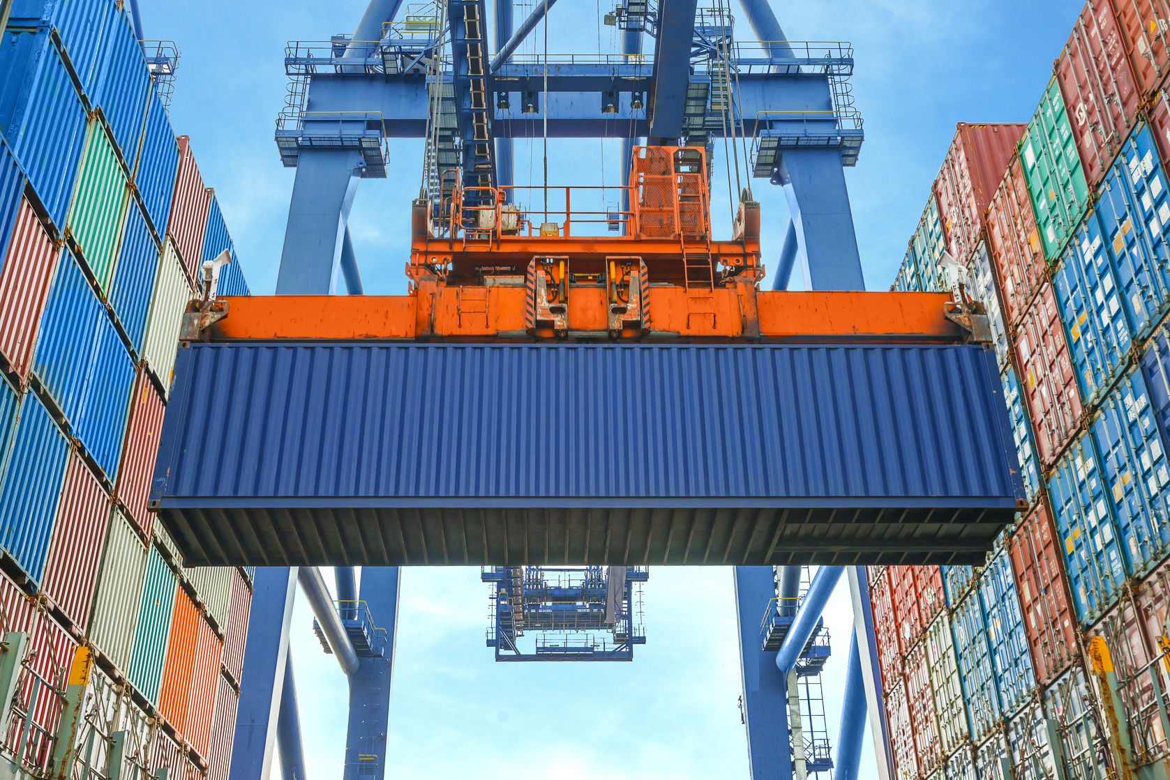 Gantry crane lifting a container between stacks at a port